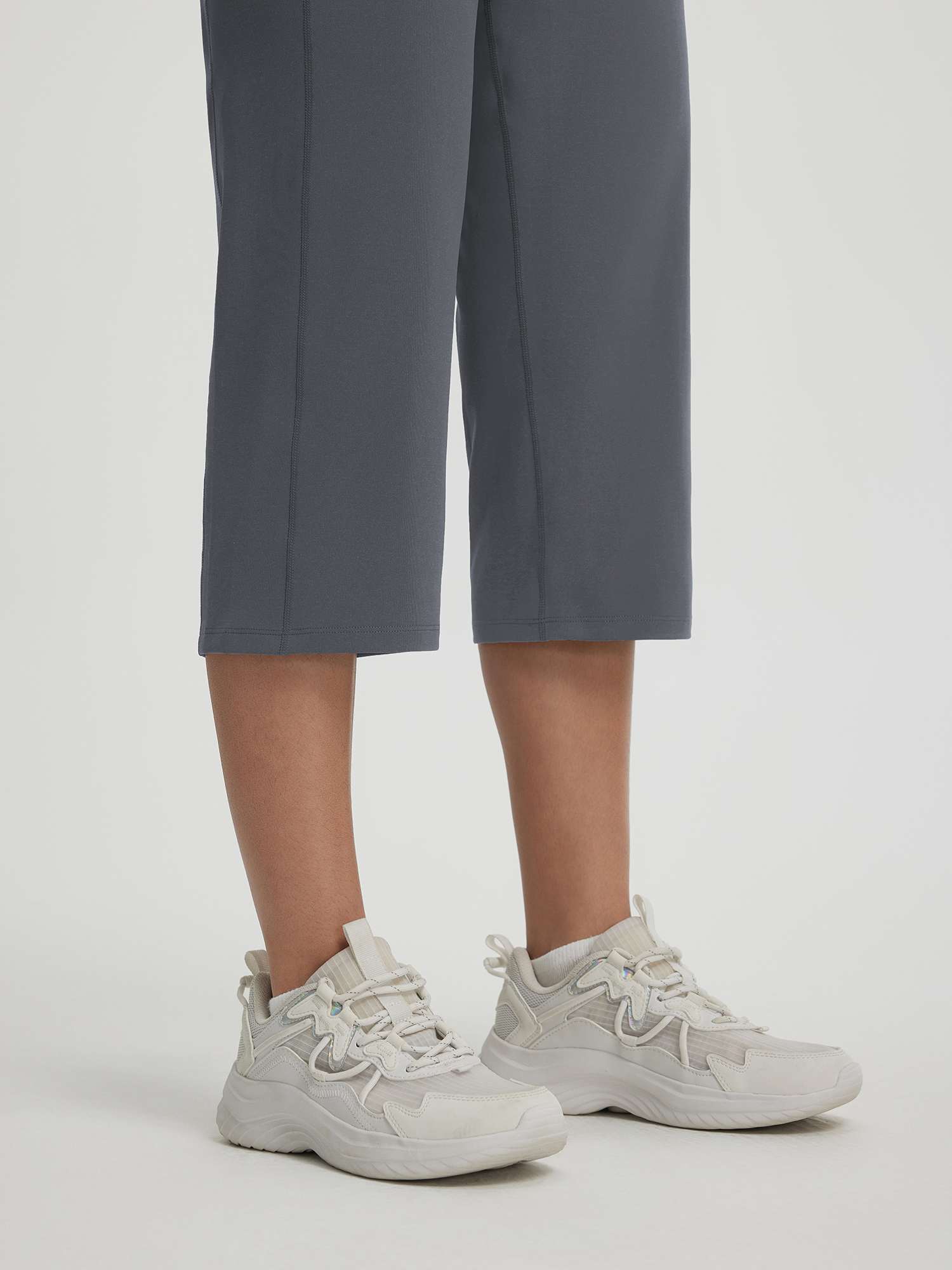 Baleaf charcoal grey 18" straight leg capri pants shown with white sneakers. #color_Dark Gray