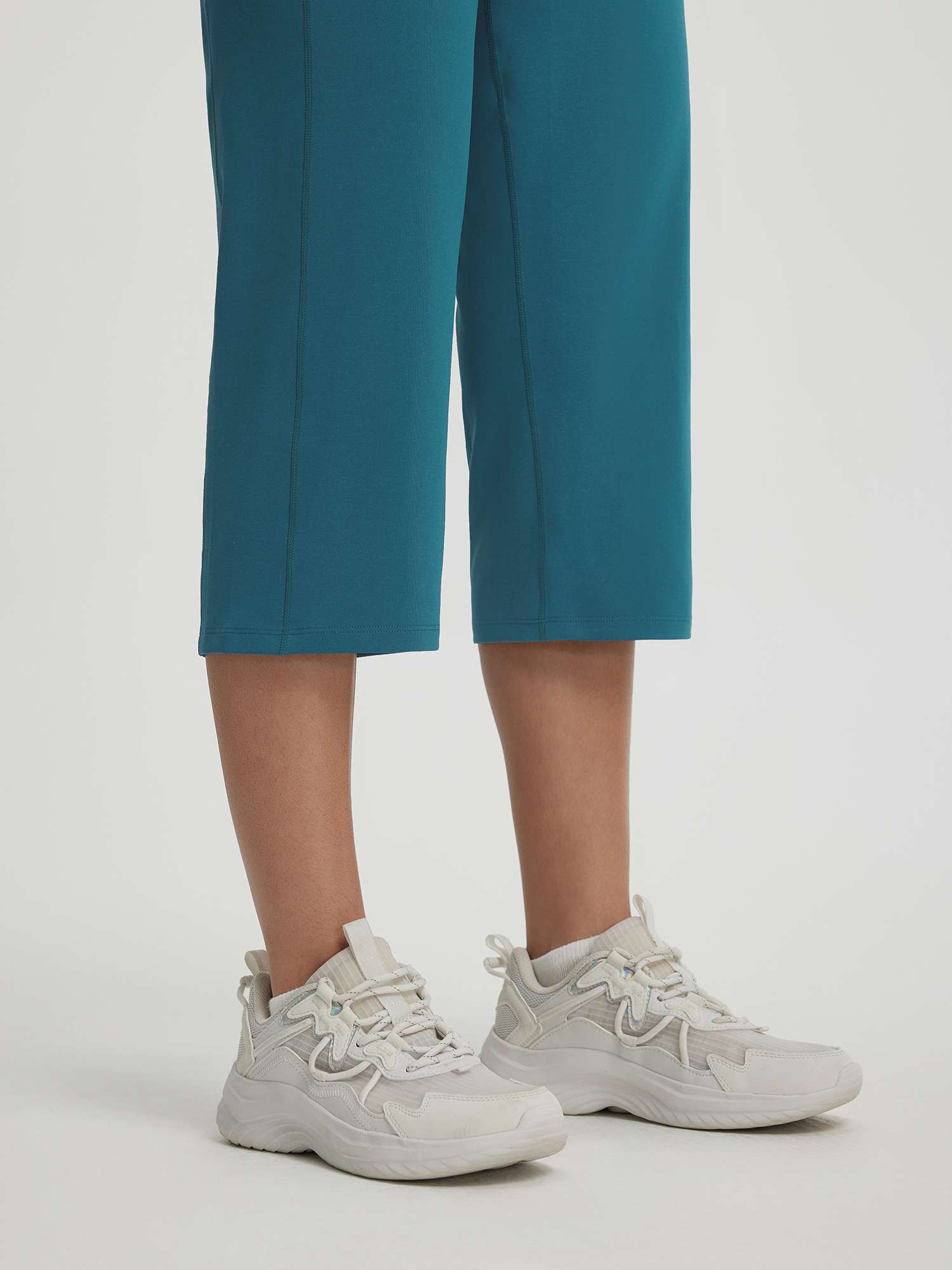 Baleaf women's 18-inch teal straight leg capri pants and white chunky sneakers. #color_Deep Blue