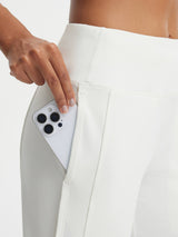 White Baleaf high-rise 17" capri leggings with a large side pocket holding a smartphone. #color_White