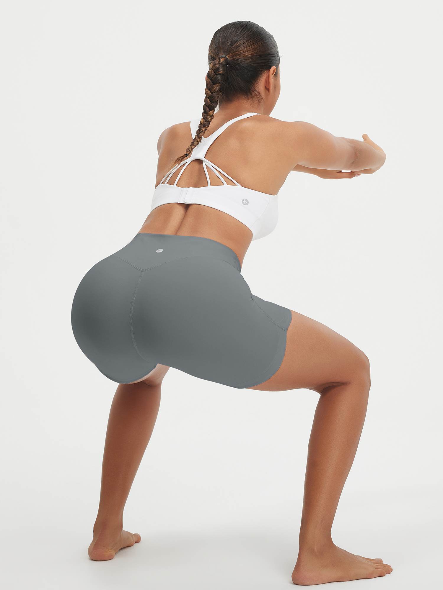 Baleaf 5" grey high-rise biker shorts on woman squatting, showcasing V-shaped hip design. #color_Gray