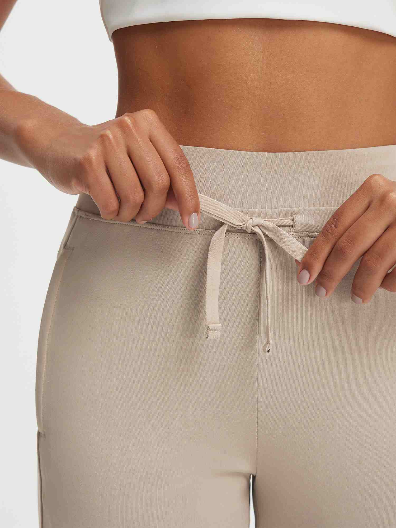 Hands adjusting drawstring on Baleaf ultra-soft high-rise beige pants waistband #color_Khaki