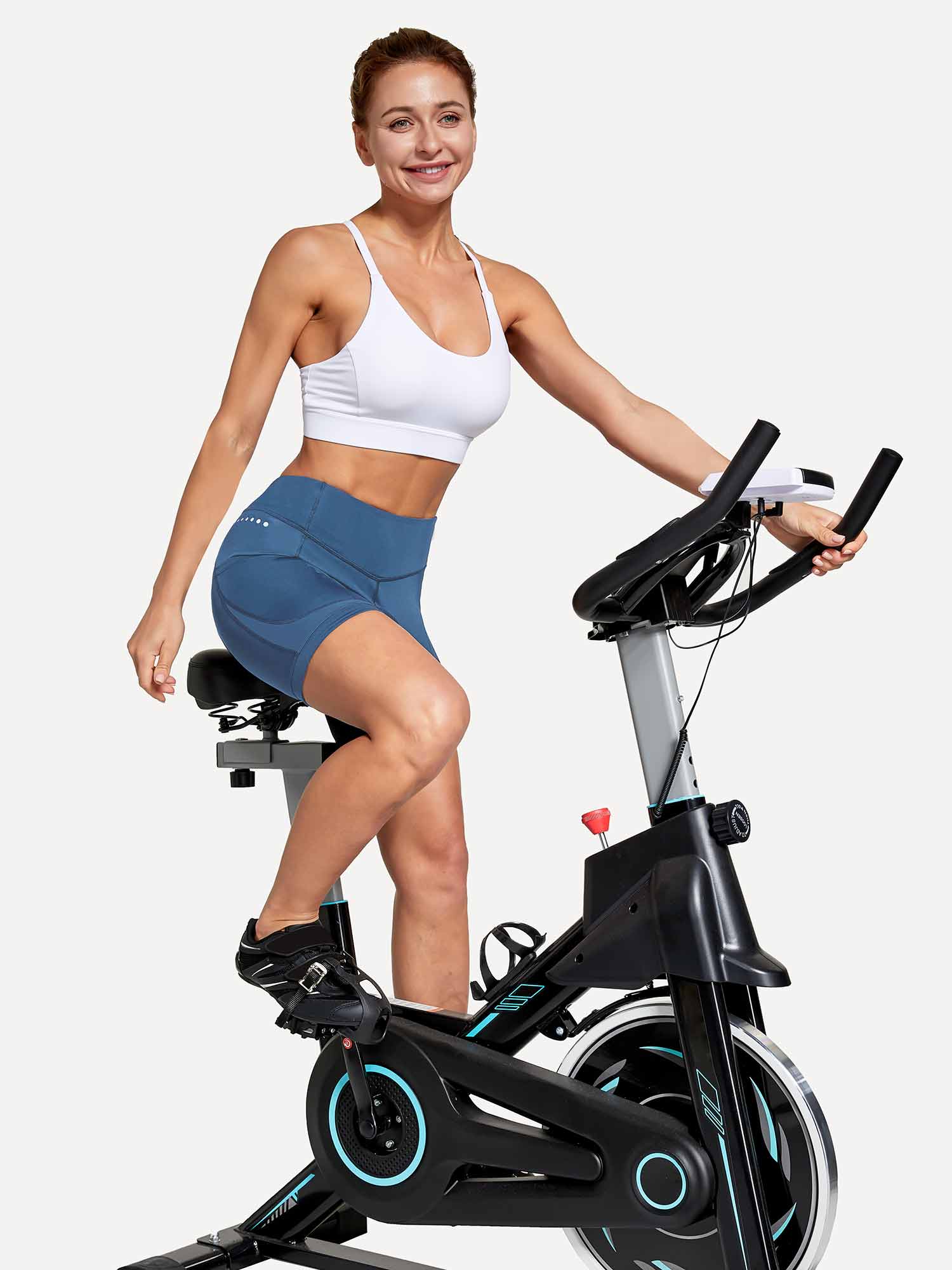 Women's blue V-waist cycling shorts with tummy control worn by fit woman on stationary bike. #color_Navy Blue