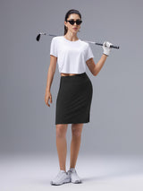 Woman modeling black UPF50+ knee-length skort with golf club and glove. #color_Black