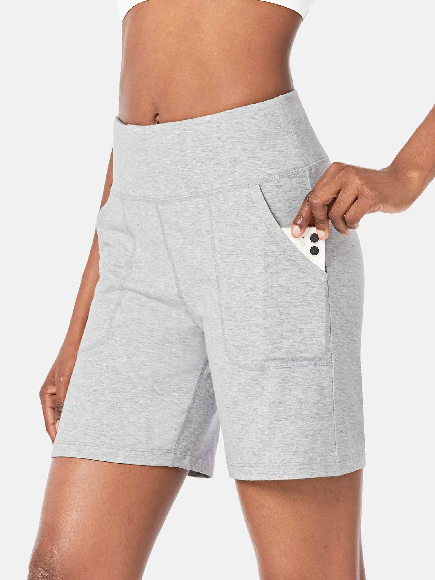 Light gray athletic shorts with a high waist and pockets, a phone is being placed into one pocket. #color_Light Gray