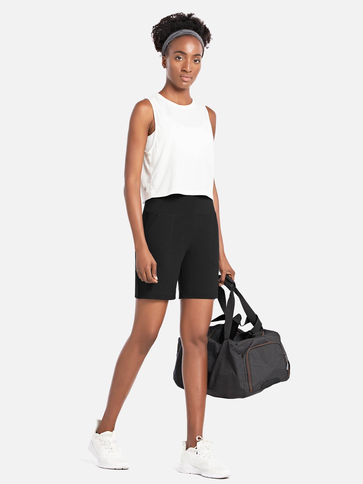 Black Laureate 7" athletic shorts on woman with white tank, sneakers, holding duffel bag. #color_Black