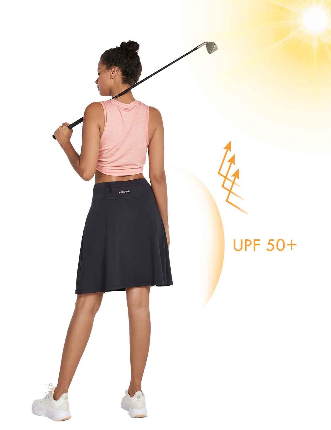 Woman in a black UPF 50+ pleated skort and pink tank top holding a golf club. #color_Black