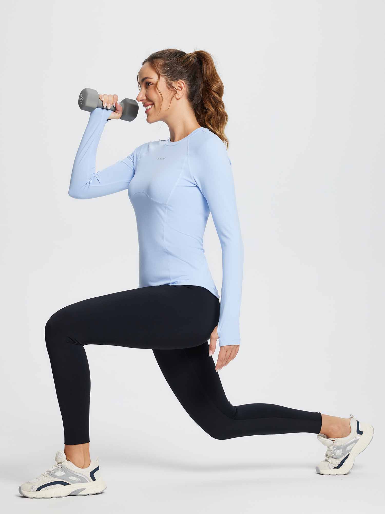 Light blue compression long-sleeve running top on athletic woman performing a lunge with dumbbell. #color_Light Blue