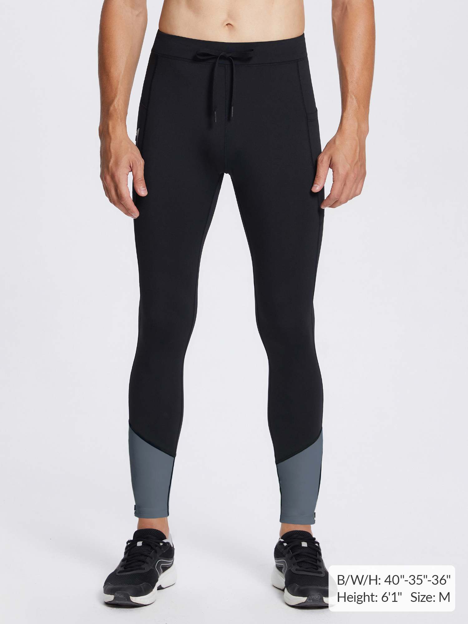 Men's black fleece lined running tights with grey ankle color-block, drawstring, and zippered ankles.