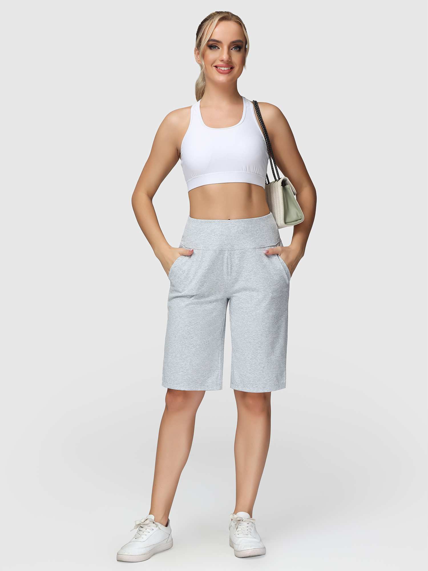 Light gray women's 12" cotton Bermuda shorts with pockets, high waist, worn with white sports bra and sneakers.