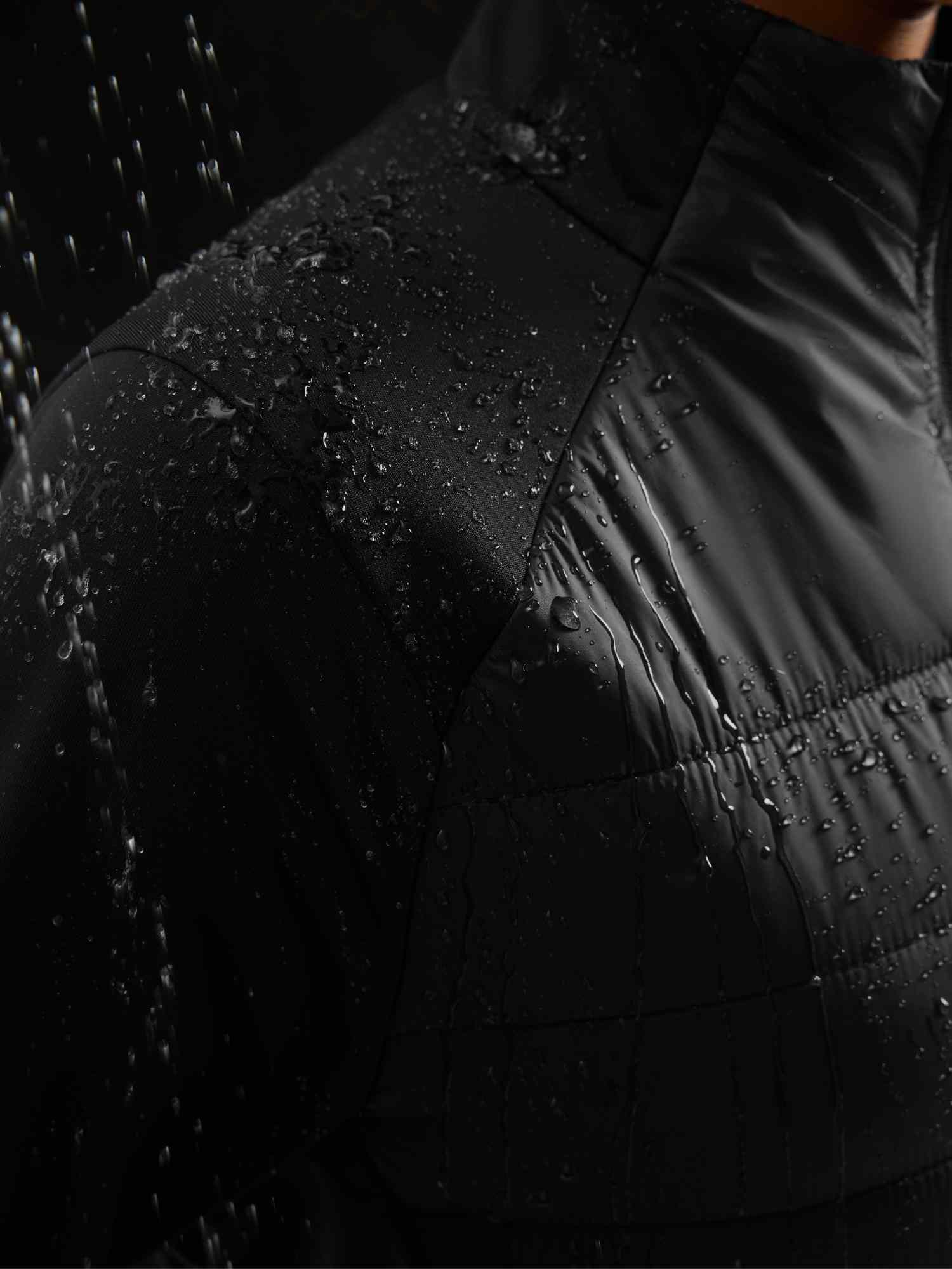 Black quilted women's outdoor jacket fabric with water droplets, showing water resistance. #color_Black
