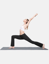 Woman in black bootcut pants and white sports bra doing a yoga lunge on a grey mat.