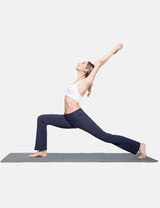 Woman in navy bootcut pants performing warrior yoga pose on mat.