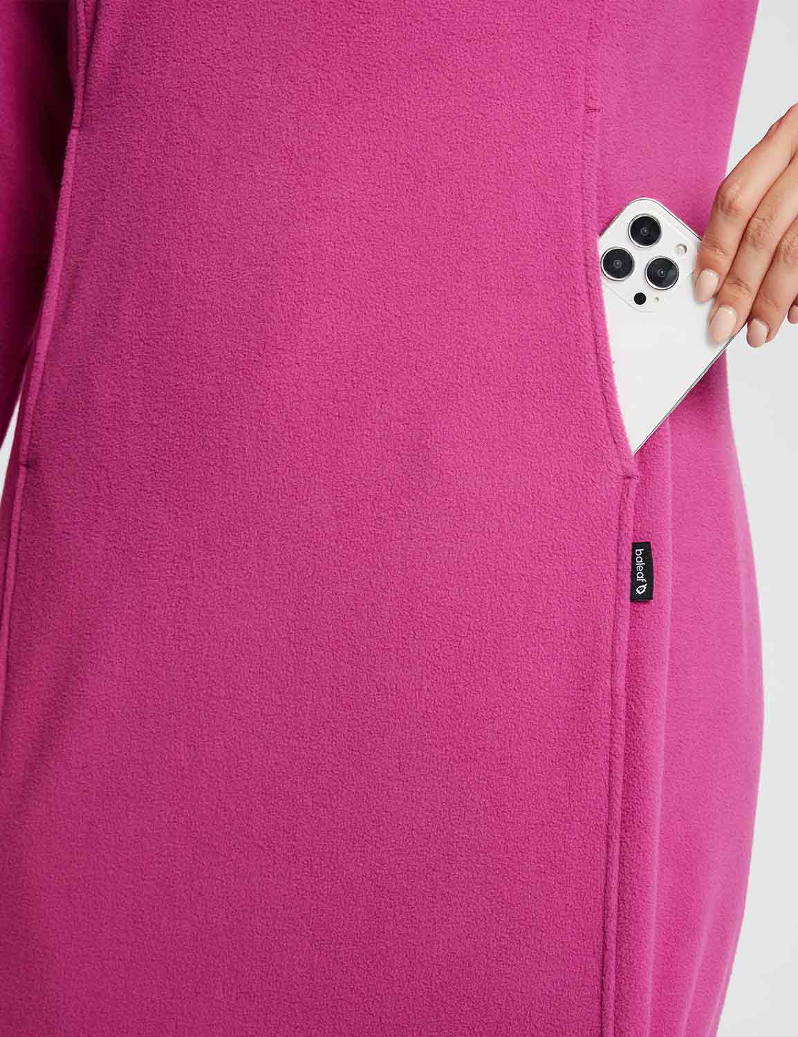 Woman places phone in pocket of vibrant pink thermal tunic dress. #color_Violet Rose