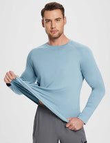 Man stretching light blue long-sleeve UPF 50+ sun shirt, highlighting breathability and relaxed fit.